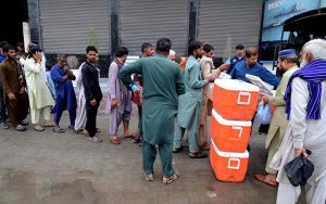 People queue for their turn to receive free food as volunteers distribute free food among people in Kotli Bahram