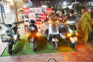Children showing interest in electric bike displayed at a vendor’s bike showroom at Latifabad