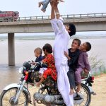 A motorcyclist enjoying and playing with his child at embankment of Indus river