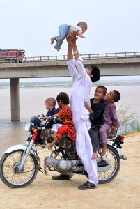 A motorcyclist enjoying and playing with his child at embankment of Indus river