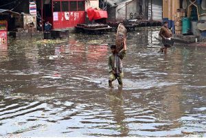 A labourer carrying empty basket on his head as he passing through the water accumulated at fruit and vegetable market after heavy rain that experienced in the provincial Capital