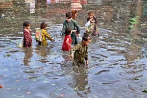 A labourer carrying empty basket on his head as he passing through the water accumulated at fruit and vegetable market after heavy rain that experienced in the provincial Capital