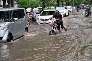 A labourer carrying empty basket on his head as he passing through the water accumulated at fruit and vegetable market after heavy rain that experienced in the provincial Capital