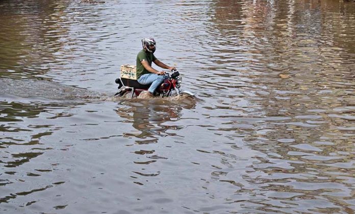 A motorcyclist passing through accumulated water on the road after heavy rain in the Provincial Capital