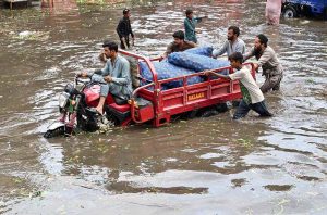 A motorcyclist passing through accumulated water on the road after heavy rain in the Provincial Capital