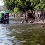 Children playing in the rain water accumulated on the road at Makka Colony