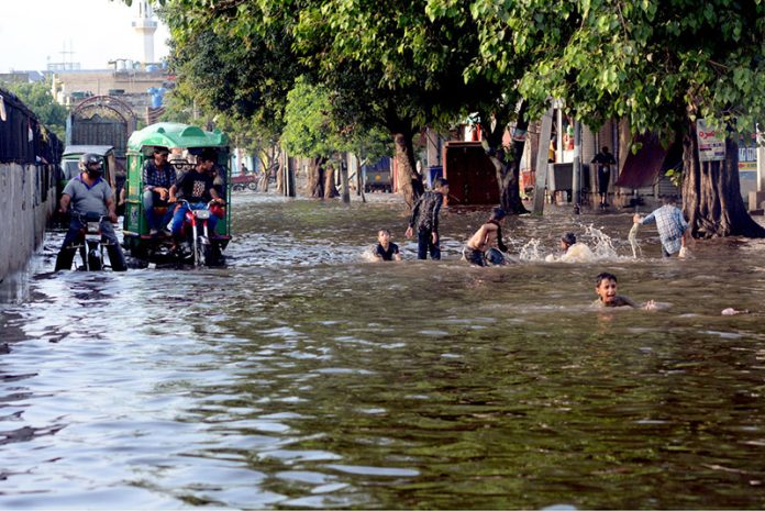 Children playing in the rain water accumulated on the road at Makka Colony