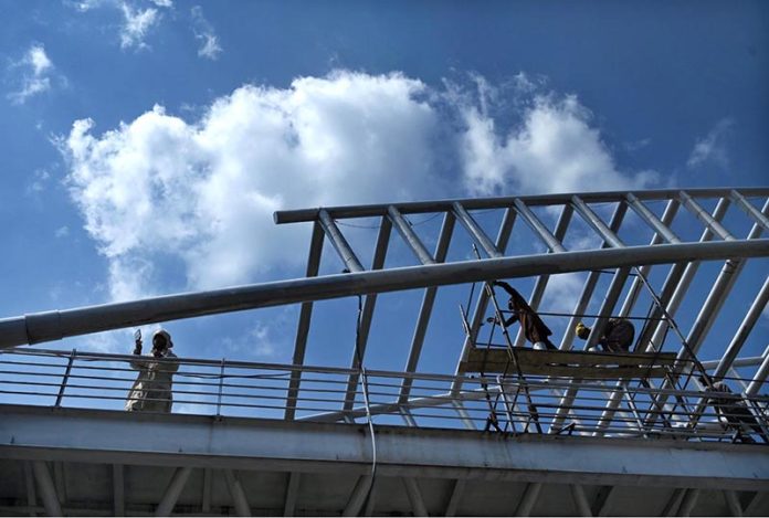 Labourers are busy paint the overhead pedestrian bridge on the Islamabad Expressway as in the background beautiful view of clouds hovering over the sky of Federal Capital