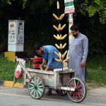A person buys a corn cob from a roadside vendor in the F-8 area of the Federal Capital