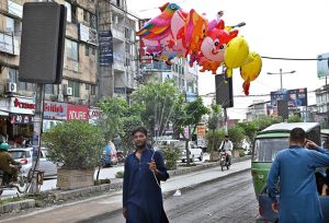 A vendor shuttles through Commercial Market, displaying balloons of various shapes to attract the customers.