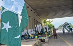 A vendor displaying national flags and other items to attract the customers at his roadside setup in connection with upcoming Independence Day celebrations in Federal Capital.