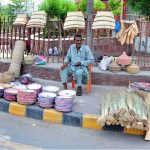 A roadside vendor displaying and selling traditional hand-woven items including baskets, mats, brooms and hand fans depicting local craftsmanship and cottage industry
