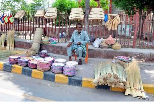 A roadside vendor displaying and selling traditional hand-woven items including baskets, mats, brooms and hand fans depicting local craftsmanship and cottage industry