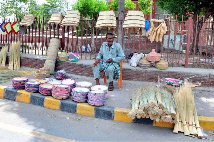 A roadside vendor displaying and selling traditional hand-woven items including baskets, mats, brooms and hand fans depicting local craftsmanship and cottage industry