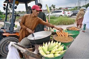 A vendor selling roasted corn outside weekly Sunday Bazaar, Peshawar Morr in Federal Capital