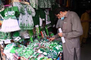 Customer selecting and purchasing national flag related badges and other items ahead of the upcoming Independence Day celebrations at Qissa Khawani Bazaar.