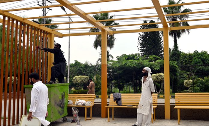 A labourer busy painting a bus stop shed on Murree Road near Allama Iqbal Park in the city