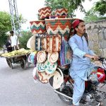 A vendor on his motorcycle loaded with handmade items to attract the customers.