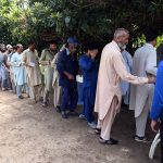 Needy people stand in a queue to receive free lunch from volunteers at F-7 Markaz