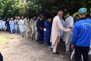 Needy people stand in a queue to receive free lunch from volunteers at F-7 Markaz