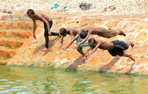 Gypsy youngsters enjoy diving into a pond near the railway station to cool off.