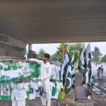 A vendor displays and sells children’s dresses in national colors along with Pakistani flags ahead of the upcoming Independence Day celebrations at Zero Point in the Federal Capital