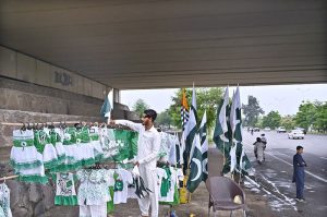 A vendor displays and sells children’s dresses in national colors along with Pakistani flags ahead of the upcoming Independence Day celebrations at Zero Point in the Federal Capital