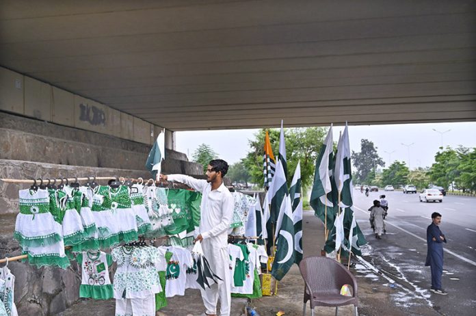 A vendor displays and sells children’s dresses in national colors along with Pakistani flags ahead of the upcoming Independence Day celebrations at Zero Point in the Federal Capital