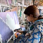 A girl learns painting at the weekly Sunday Bazaar, Peshawar Mor in the Federal Capital