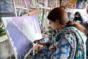 A girl learns painting at the weekly Sunday Bazaar, Peshawar Mor in the Federal Capital