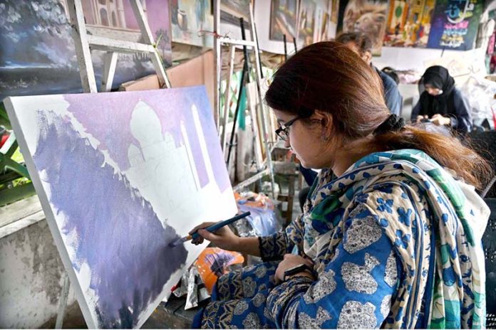 A girl learns painting at the weekly Sunday Bazaar, Peshawar Mor in the Federal Capital