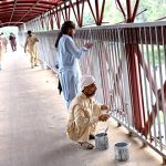 Workers busy painting a pedestrian bridge at Zero Point in the Federal Capital