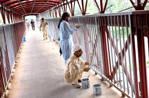 Workers busy painting a pedestrian bridge at Zero Point in the Federal Capital