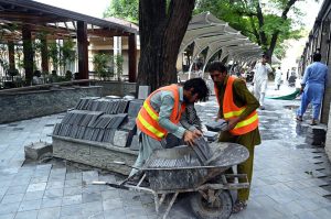 Laborers load tuff tiles onto a cart to be fixed on the footpath as part of renovation work at Melody Food Park in the Federal Capital.