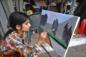 A girl learns painting at the weekly Sunday Bazaar, Peshawar Mor in the Federal Capital