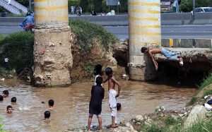 Youngsters bathe in stagnant rainwater along IJP Road in the Federal Capital.