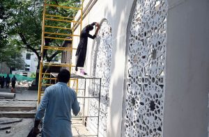 Laborers load tuff tiles onto a cart to be fixed on the footpath as part of renovation work at Melody Food Park in the Federal Capital.