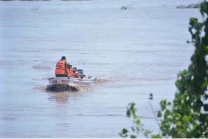Rescue workers repair a lifesaving boat before launching operations as the swollen River Chenab carries heavy floodwater through Chiniot district.