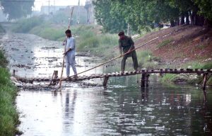 WASA workers are busy cleaning sewerage nullah during rain in the city