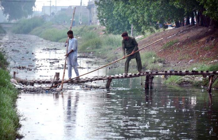 WASA workers are busy cleaning sewerage nullah during rain in the city