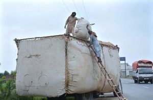 Labourer loading chaff (husk from wheat) from a delivery truck.