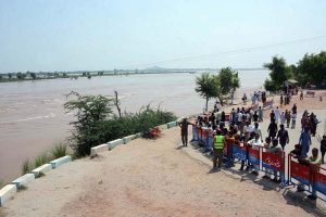Rescue workers repair a lifesaving boat before launching operations as the swollen River Chenab carries heavy floodwater through Chiniot district.