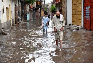 People passing through rainwater accumulated in the street after heavy rain in Provincial Capital.