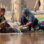 Nomad women washing clothes along a canal bank, carrying out daily household chores in a traditional way