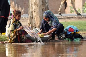 Nomad women washing clothes along a canal bank, carrying out daily household chores in a traditional way