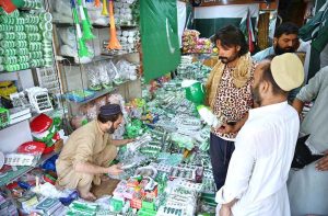 Customers selecting and purchasing national flag printed caps and other items ahead of the upcoming Independence Day celebrations at Qissa Khawani Bazaar.