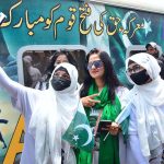Women passengers take a selfie with a cell phone in front of the Thar Desert Safari Azadi Train at the railway station, traveling from Karachi to Khokhrapar as part of the 78th Independence Day and 'Marka-e-Haq' celebrations