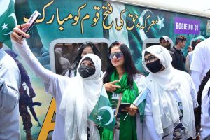 Women passengers take a selfie with a cell phone in front of the Thar Desert Safari Azadi Train at the railway station, traveling from Karachi to Khokhrapar as part of the 78th Independence Day and 'Marka-e-Haq' celebrations