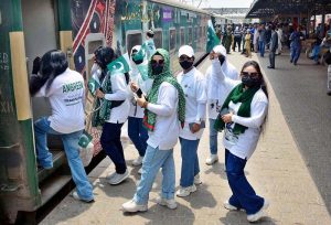 Women passengers take a selfie with a cell phone in front of the Thar Desert Safari Azadi Train at the railway station, traveling from Karachi to Khokhrapar as part of the 78th Independence Day and 'Marka-e-Haq' celebrations