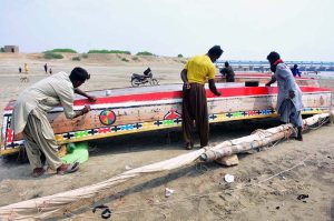 Fishermen add fresh colors on their boats on the dried riverbed of the Indus.